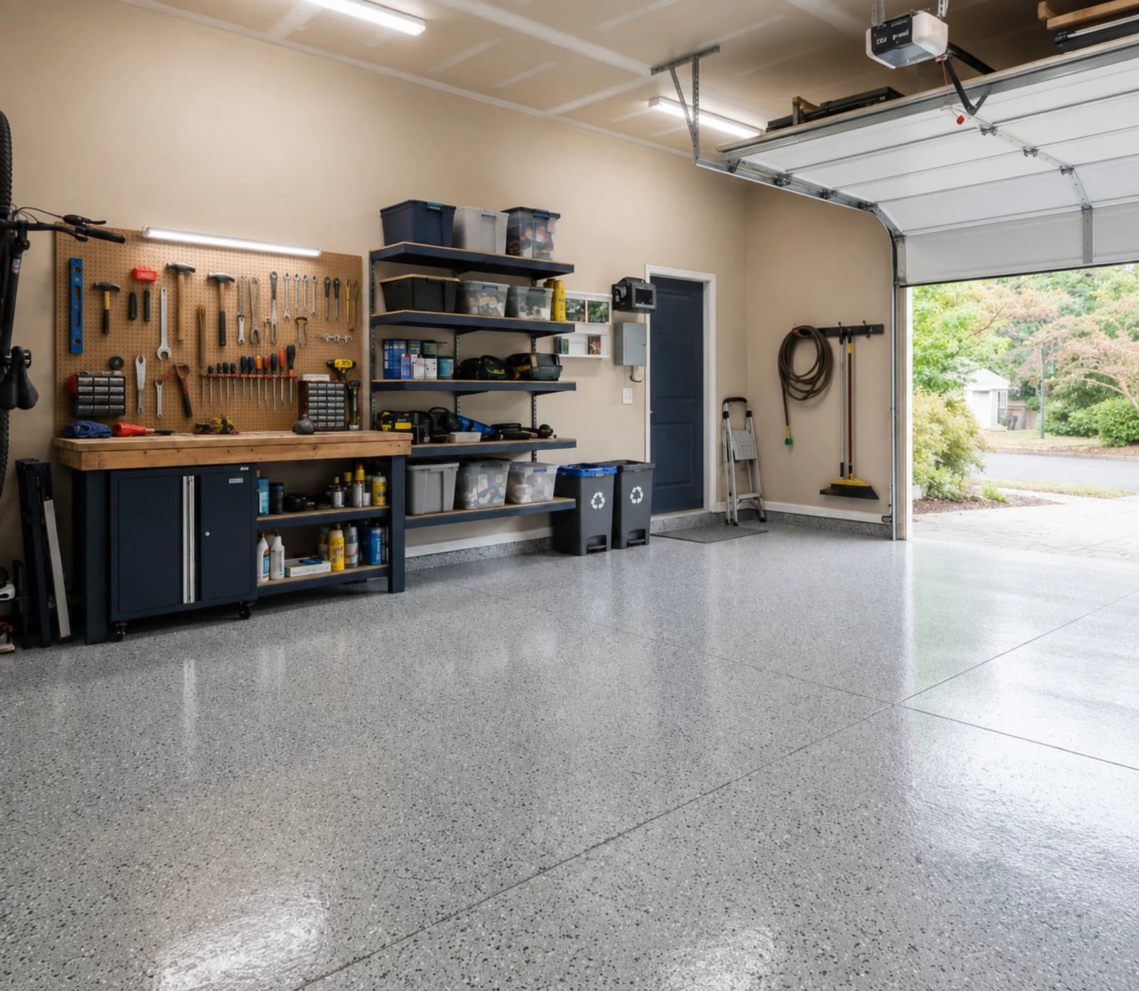 Finished residential garage with a clean light-gray garage floor, organized workbench, and open garage door